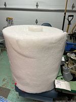 Side view of large thick white batting roll in garage setting showing full height and width