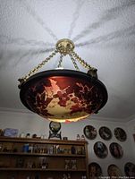 Chandelier hanging from ceiling showing floral glass shade, brass chains and ceiling canopy