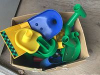 Top view of colorful plastic Marble Works toy parts including ramps, tubes, and connectors inside a cardboard box.