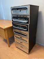 Three-quarter front view of the dresser showing chrome drawer fronts and black painted body