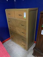 Overall view of the wood dresser showing five drawers, veneer pattern, and metal handles. Photos show condition and dimensions visually.