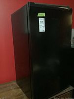 View of closed black Hisense bar fridge with visible label showing maxsold lot number and handwritten notes.