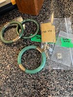 Wide view of three jade bracelets, pearl strand and sterling pendant in bag