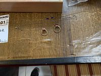 Overview of two necklaces and two rings laid out on wood surface