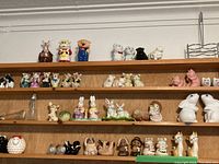 Four wooden shelves with assorted decorative salt and pepper shakers mostly in animal shapes and small figurines