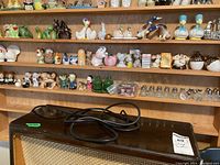 Four wooden shelves filled with a variety of decorative salt and pepper shakers in animal and novelty shapes, showing the overall collection and setting.