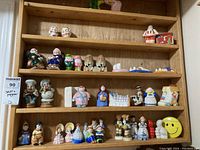 Multiple shelves of assorted ceramic salt and pepper shakers featuring a variety of character and household designs.