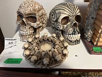 Front view of the three skull sculptures placed side by side showing intricate detailing and designs on all pieces.