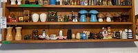 Full shelf shot showing a large assortment of salt and pepper shakers and figurines including wooden grinders, ceramic mushrooms, animal, lighthouse, and ship-shaped shakers.