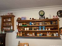 Photo showing two wooden wall shelves mounted on a wall filled with collectible holiday-themed salt and pepper shakers and figurines