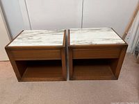 Front view of two wood-framed side tables with marble tops and open shelf below