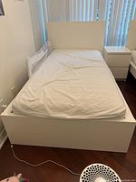 Full view of white IKEA twin bed with fitted sheet showing headboard, side rails, and footboard.