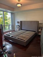 Front view of grey upholstered queen bed frame in room