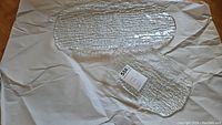Two textured glass platters lying on wrapping paper, showing their clear smooth tops and textured backs.
