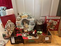 Wide view showing assortment of Fitz and Floyd Christmas decorations, a decorative wreath, candles, and various small ornaments inside a box.