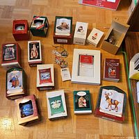 Photo of Hallmark Keepsake and other boxed holiday ornaments arranged on floor, showing multiple designs and original packaging.