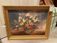 Frontal image of the entire framed painting showing the artwork and the frame resting on the ground.