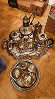 Display of larger silverplate tea and coffee service on large tray with ornate handles and finials