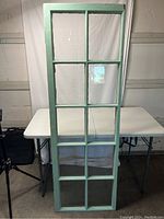 Full front view of the antique 10 pane window with turquoise paint showing some wear and intact glass panes.