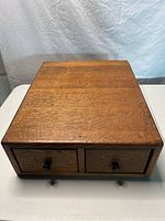 Top front view of antique 2 drawer wooden card catalog cabinet showing wood grain and condition of surface.