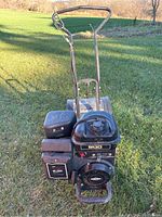 Front angle view of tiller showing engine housing, handlebars, and tines