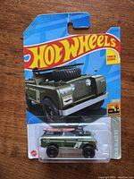 Front view of factory sealed Hot Wheels Land Rover Series II Baja Blazers car in original packaging showing olive green Land Rover with roof accessories.