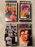 Front side of the new, factory sealed VHS tapes showing colorful cover art for The King and I, The Bridge on the River Kwai, Citizen Kane, and Dead Man Walking.