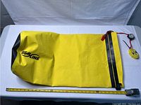 Yellow Seal Line Baja dry bag laid flat with measuring tape showing size, positioned on white surface.