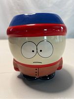 Front view of ceramic coffee mug shaped as South Park character Stan with wide eyes, blue/red hat, and brown coat.