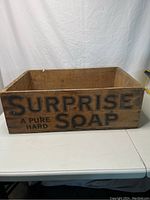 Photo of front side of vintage wooden soap box showing 'SURPRISE SOAP A PURE HARD' lettering.