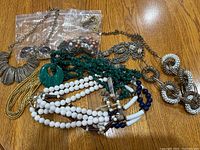 Full view of the assortment of necklaces showing variety in styles, materials, and colors including beads, chains, and carved pieces.