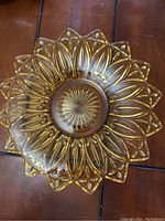 Top-down image of the amber yellow glass plate showing petal design and sunburst center.