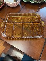 Amber vintage Indiana Glass divided serving tray showing embossed fruit designs in the compartments, ribbed edges and side handles.