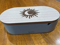 Closed blue Bizou jewelry box showing light wooden lid with sun and moon engraved design on top