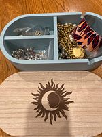 Top-down view of blue jewelry box with sun/moon lid and costume jewelry inside compartments