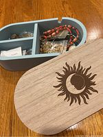 Blue Bizou jewelry box with sun and moon design on the lid, top view without lid showing compartments with costume jewelry