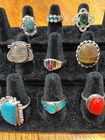 Photo of nine assorted sterling silver rings with various stones arranged on black ring display stand