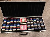 Interior view of the open poker chip case showing poker chips, playing cards, dice, and dealer button organized inside.