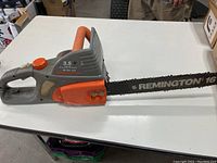 Side view of electric chainsaw showing the entire body, front handle, and the 16 inch cutting bar with chain.