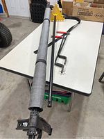 Full view of retractable load handler laid on a table in a garage setting, showing metal mounting bracket, roll out fabric, and spare handle.