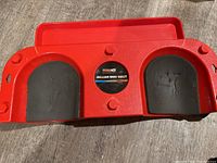 Top view of red plastic rolling knee dolly showing foam knee pads and central brand label.