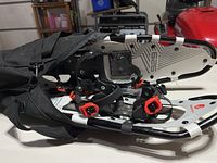 Snowmountain snowshoes inside the black carry bag showing the metal frame and adjustable bindings with red buckles.