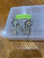 Front view of the pair of sterling silver Taxco Monteros earrings with shield top and three feather dangles each.