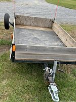 Front view showing hitch coupler, safety chains, jack, wood front rail and diamond-plate floor