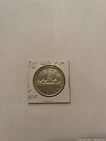 Front side of the 1953 Canadian silver dollar coin showing the canoe design, year, and denomination, secured in a cardboard holder with handwritten notes.