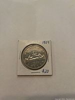 Reverse side of 1959 Canadian silver dollar coin showing canoe scene and date.