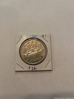 Front side of 1960 Canadian silver dollar showing the voyageur and indigenous person in a canoe with inscriptions.