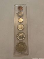 Top and bottom view of six coins in transparent plastic holder showing obverse and reverse sides of each coin.