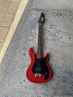 Front view of red Tokai electric guitar with black pickguard on concrete floor.