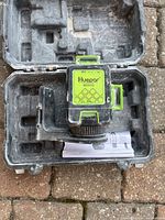 Huepar B03CG laser level inside carrying case showing front view with level vials and control knob.